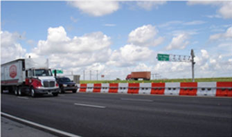 This photo shows longitudinal channelizing devices arranged to provide a barrier between a highway and a construction zone in the highway median.
