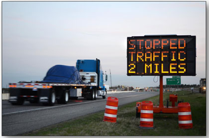Photograph of a portable dynamic message sign used to indicate queues along I-35.  The sign reads 'STOPPED TRAFFIC 2 MILES.'