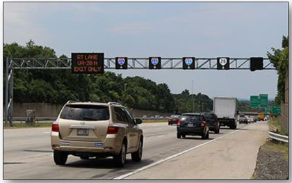 Photograph showing the ATM installation along I-66 in Virginia.  A sign bridge is shown with lane use control signals over each of the lanes of traffic, 4 of which show a route shield.  The rightmost sign over the shoulder is blank.  A DMS is on the left with 'RT LANE VA-28N EXIT ONLY' shown on the sign.
