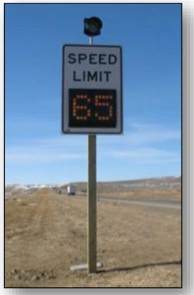 Photograph of a dynamic speed limit sign used in Wyoming.  The sign is a standard regulatory speed limit sign with a variable inset with the speed '65' shown on it.