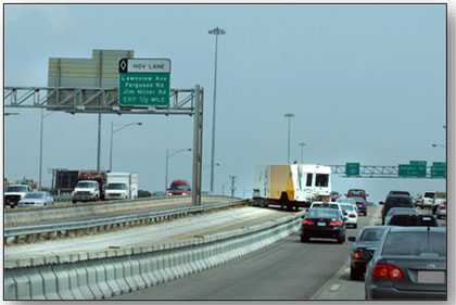 Photograph of the moveable barrier used as part of the dynamic reversible lane on I-30 in Dallas, Texas.  The photo shows the barrier being moved by the machine.