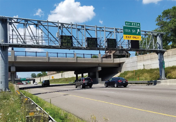 Minnesota highway with overhead, real-time electronic messages warning drivers of 'Slow Traffic Ahead' helping them prepare to reduce speed and avoid potential rear-end collisions.