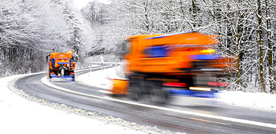 Two working snow plows on winter road.