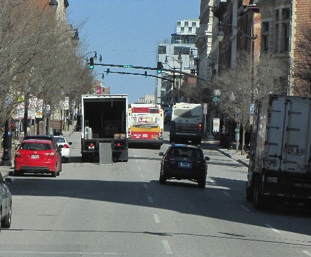 busy downtown Baltimore street with a parked delivery truck blocking the left of three lanes