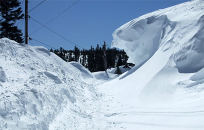 Heavy snow build-up on a Truckee roadway. Snow pile appears to be at least ten feet or higher.