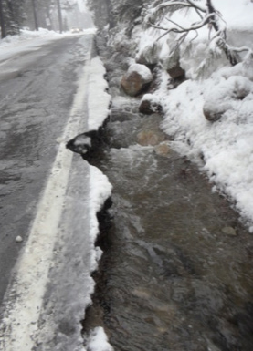 Impact of flooding on Truckee roadways. Photograph shows erosion of a roadway edge due to water running along its side.