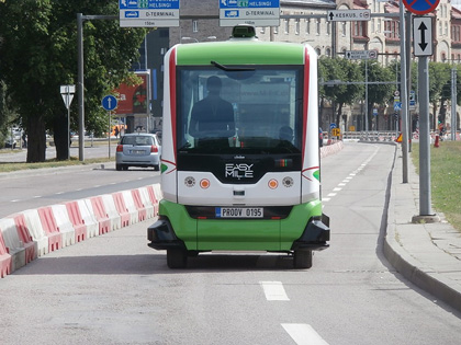 Figure 13 is a photo of a small driverless shuttle van on roadway section separated from other traveling vehicles next to the curb.