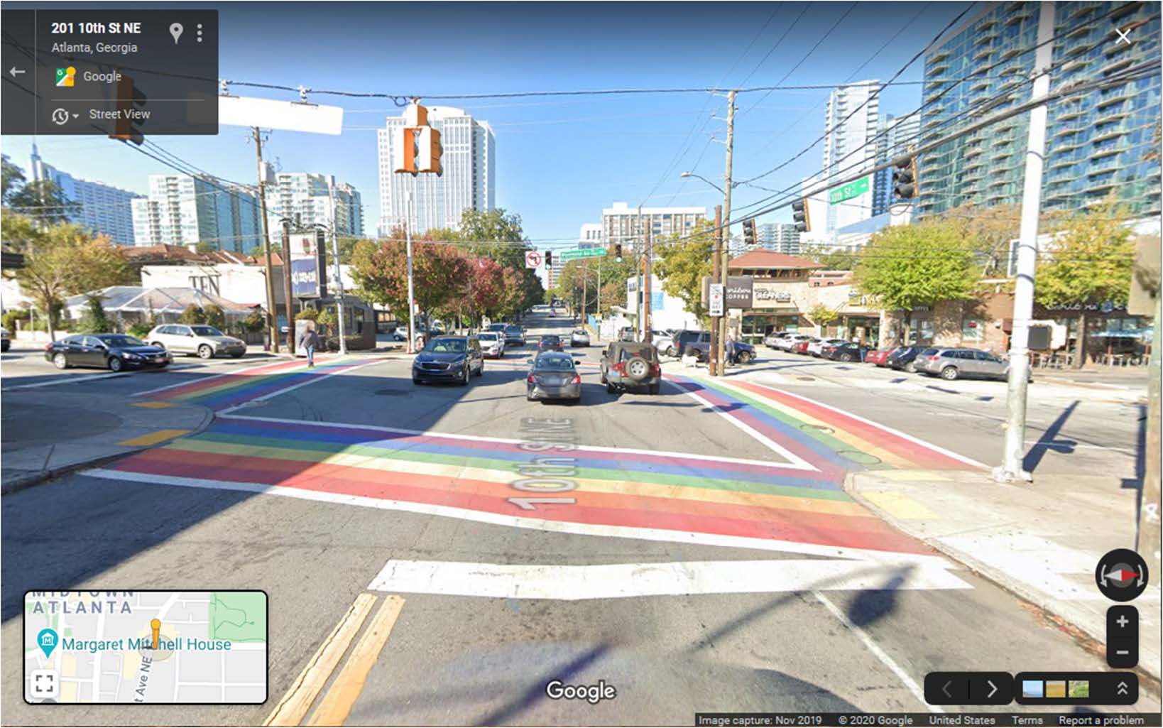 Street view image shows an intersection with non-traditional crosswalks, that are rainbow-striped.