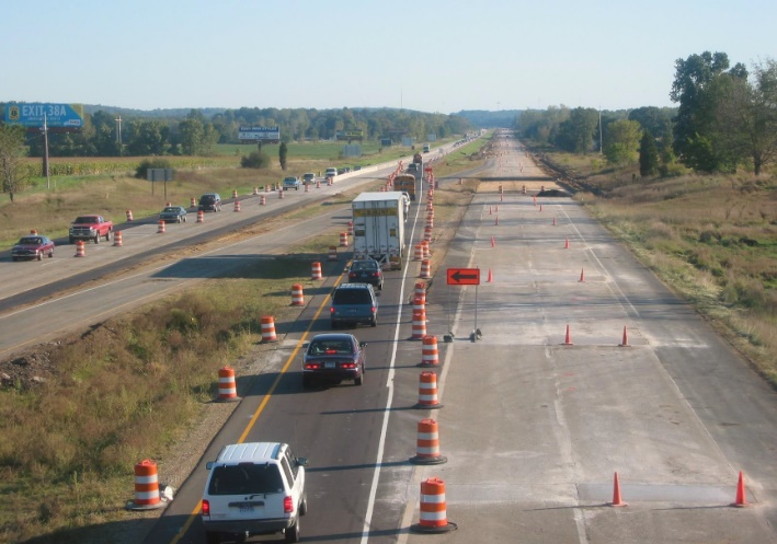 Aerial view of traffic on compressed into one lane on a three-lane rural highway with two lanes closed to traffic for work zone activity.