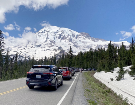 A backed up line of cars on a two-lane roadway with Mount Rainier in the background.