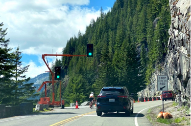 A portable temporary traffic signal on a two-lane roadway in a mountainous area. The road has been narrowed to one lane due to construction, and the traffic signals take the place of flaggers.