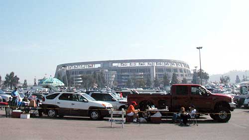 photo of Qualcomm Stadium behind a parking lot filled with cars and picnicking patrons