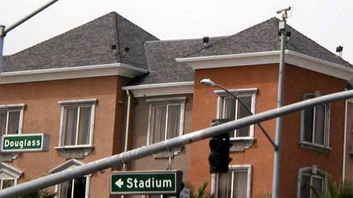 closed-circuit television camera mounted on top of a light pole at an intersection and positioned to view a stadium access road