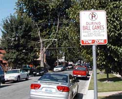 photo showing a residential street sign that states "no parking during ball games except vehicles displaying resident permits. Tow Zone"