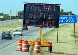 a photo showing a portable changeable message sign, located on a freeway shoulder, stating "concert traffic – right lane"