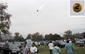 a large helium balloon with the number "2" flies high above a particular venue parking area