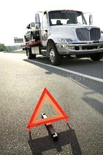 photo of flatbed truck and portable, reflective hazard triangle road sign