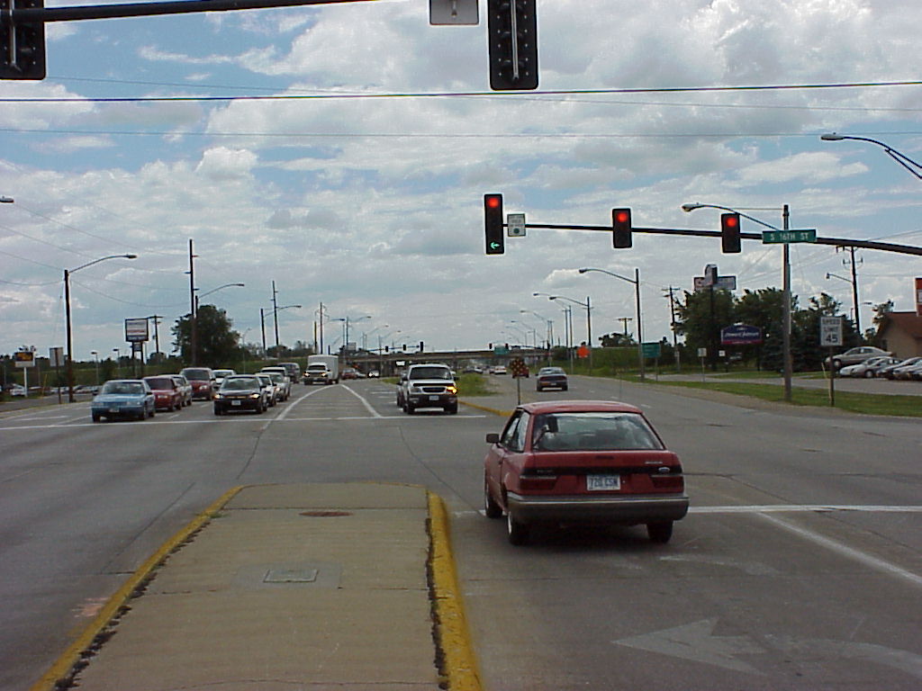 photo of cars stopped at intersection with three overhead traffic signals