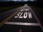 photo of roadway lane with the word slow and a right-curving arrow between two horizontal solid lines