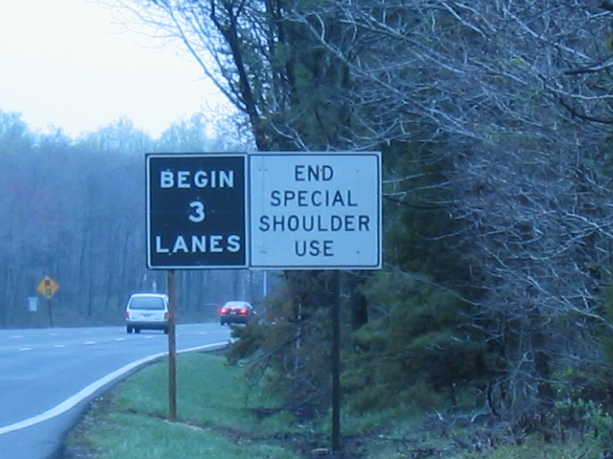 photo showing sign to the right of a roadway with the words "Begin 3 lanes, end special shoulder use"