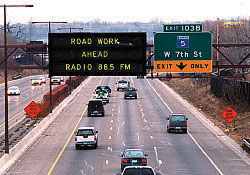 Photograph of traffic sign informing travelers of work zone ahead and highway advisory radio station
