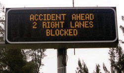Photograph of dynamic message sign warning travelers of accident ahead and blocked lanes