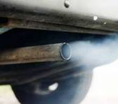 Photograph:  Close up photograph of an automible's exhust pipe. In the photograph a grayish blue gas is being emitted from the tailpipe.