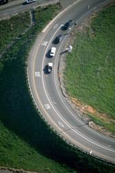 Photograph:    An aerial photograph of a freeway entrance ramp with one metered general all purpose lane and one HOV lane.  The photograph shows three vehicles queued at the ramp meter with another vehicle pulling away from the ramp meter.  