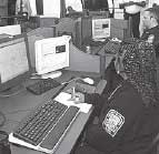 Photograph - A public safety operator (woman) is entering data into a computer.