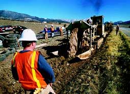 photograph of workmen using a trench digging machine to lay cable