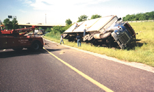 Photograph showing an overturned  tractor on the side of a road.