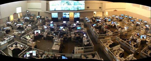Panoramic view of the operations floor of the Combined Traffic, Emergency, and Communications Center in Austin, TX showing modular office space and shared video displays for multiple operations agencies.
