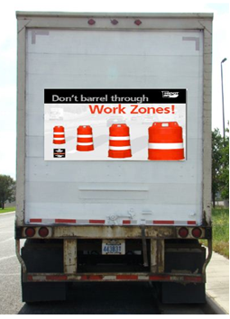 Back of an 18-wheel commercial truck with a 'Don't Barrel Through Work Zones' poster mounted to the back door.