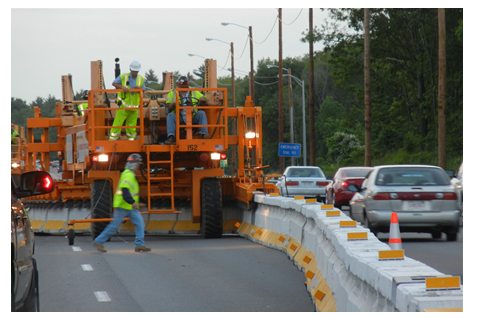 Workers moving the barrier using a zipper truck.