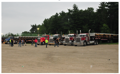 Photo depicts DOT staff and contractors walking to large trucks in preparation of transporting precast structures to the work site.