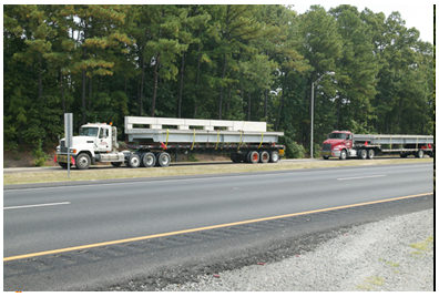 Large trucks transporting precast bridge segments to the work zone.