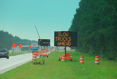 Image shows a work zone with a dynamic message sign displaying 'Slow Trucks Ahead'