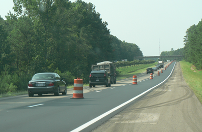 Image shows a single lane of traffic next to a lane closure.