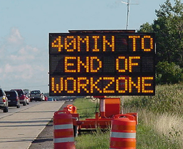 A portable changeable message sign on the side of a congested highway advises drivers that it would be 40 minutes to the end of the work zone.