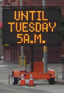 Photo of portable sign on roadway with the message "Until Tuesday 5 A.M."