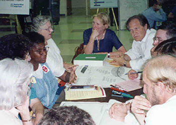 Photo of a public meeting, with participants sitting around a table.