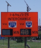 Photo of a work zone sign providing two sets of travel times advising travelers how long it will take to reach an interchage, one via I-275 and the other via I-94.
