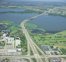 Aerial photo of a highway with a bridge stretching across a lake.