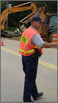 Photo of a police officer in an orange safety vest in a work zone.