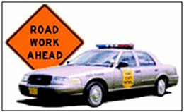 Photo of a police cruiser and a Road Work Ahead warning sign.