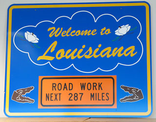 Photo of a Welcome to Louisiana sign with a Road Work Next 287 Miles warning sign below the welcome message.