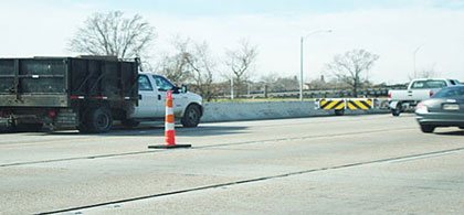 Photo of a truck with a truck mounted attenuator in front of a work vehicle in a work zone.