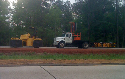 Photo of a truck with a truck mounted attenuator behind a work vehicle on a roadway.