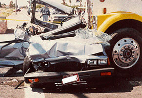 Photo of a car crashed into the front of a truck.
