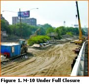Picture shows a portion of the M-10 with the roadway surface removed and subsurface exposed.  Pieces of construction equipment have full access to the facility and work unhindered.
